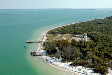 Aerial view of emerald green water and the lighthouse and beautiful beaches of Egmont Key St. Petersburg, Florida - Docks , sailboats and a pontoon boat in the waters